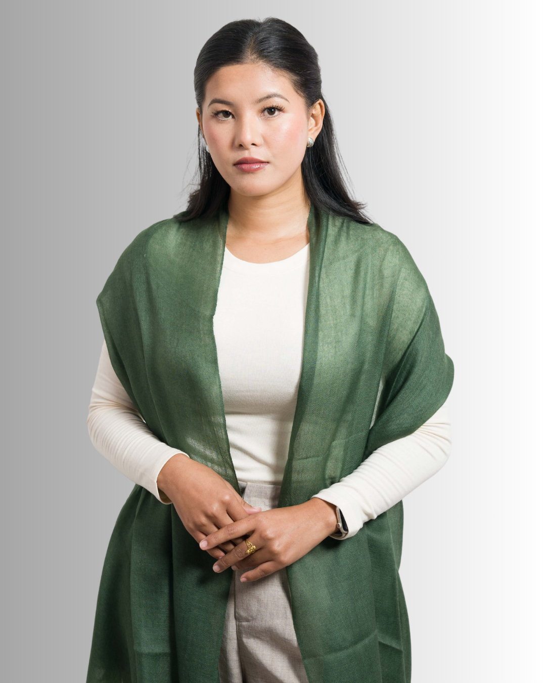 Woman wearing a green scarf over a white shirt against a gray background